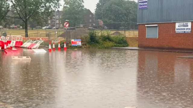 Lots of surface water from flash foods outside a building next to a park