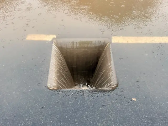 Water flowing into a drain with the manhole cover removed