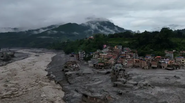 Wide shot of one affected village near the Trinshui River showing extensive damage, large areas covered by water and mud