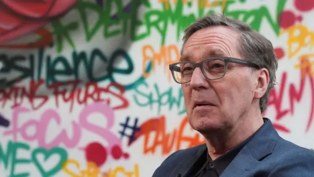 Alan Milburn is pictured in front of a graffitied wall