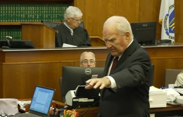 A lawyer in a suit stands in court