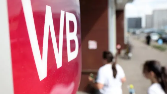 Two women enter a pick-up point in Moscow, with WB branding