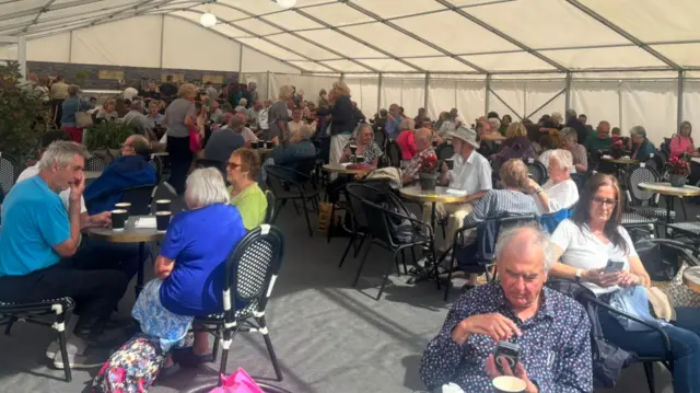 pobl mewn caffi ar y maes