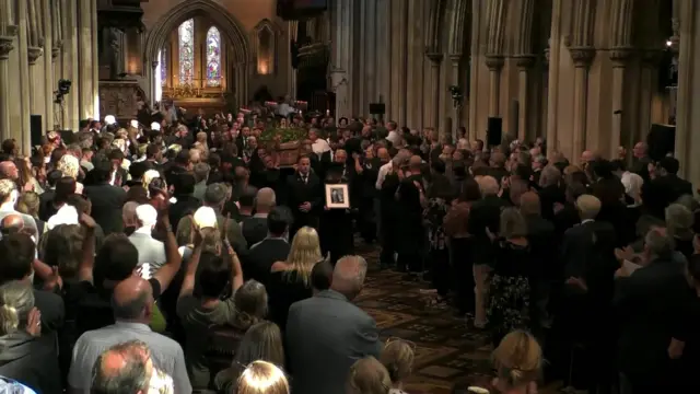 Coffin carried down the centre of the aisle.