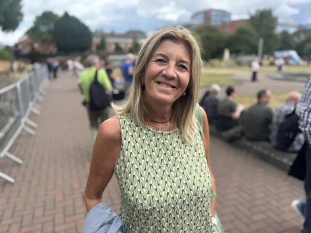 A woman in a green dress snats on a red-brick path