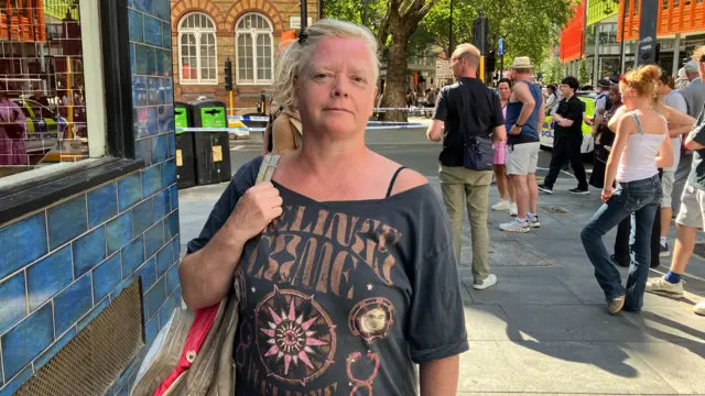 A woman looks at the camera and holds her bag strap on the shoulder