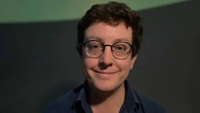 Matt Bothwell smiling in front of a black background