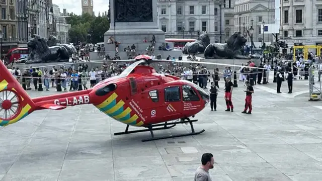 A red helicopter lands in London's Trafalgar Square