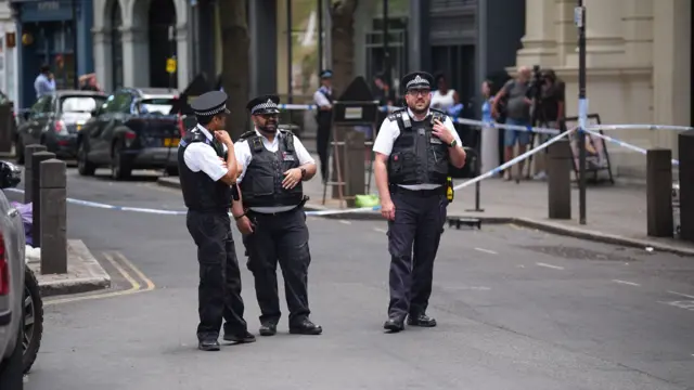police officers near the scene on Endell Street in Covent Garden, central London, after four men were stabbed