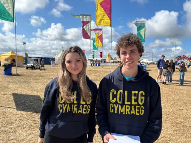 Gwenan a Tomos o'r Coleg Cymraeg yn crwydro’r maes, a'r ddau yn dweud eu bod yn edrych ymlaen yn eiddgar at noson agoriadol Maes B