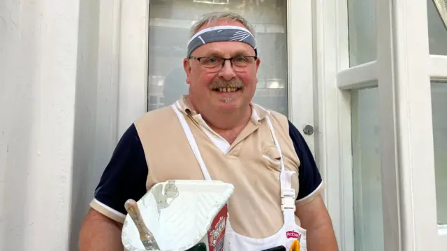 Tim Keates pictured with a paint bucket. He is wearing glasses