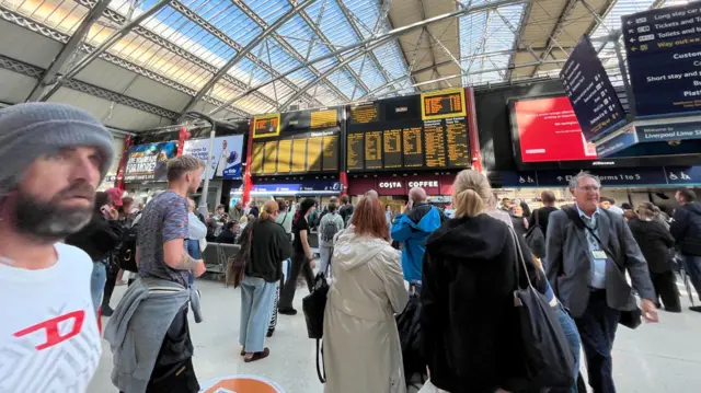 Liverpool Lime Street departures board and with delayed passengers looking up