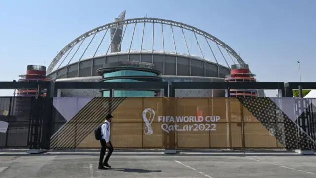 A migrant worker walks past Khalifa International Stadium in Doha, Qatar on 19 November 2022, one day before the FIFA World Cup Qatar 2022