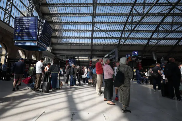 Commuters stand in a concourse at Lime Street railway station in Liverpool