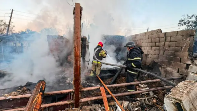 A man extinguishes a fire in a smouldering smokey building