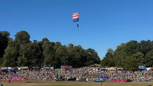 A parachuter is about to land in front of a large crowd