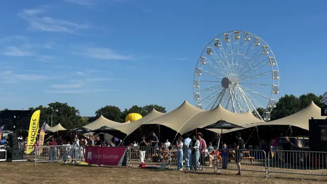A merry-go-round with tents and queues of people