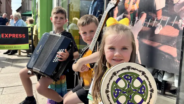 Three siblings holding instruments