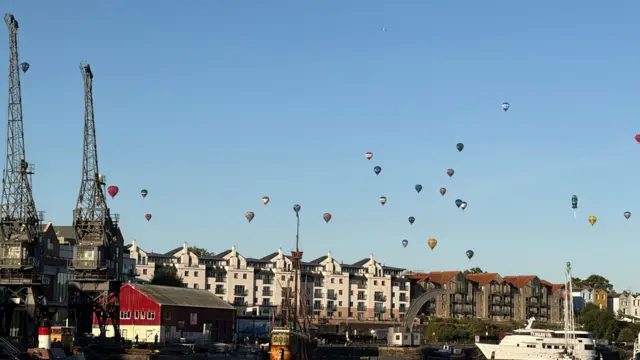 Lots of balloons in the sky over Bristol harbourside, with the iconic cranes in the foreground.