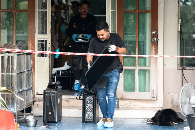Two officers carry computer equipment out of house