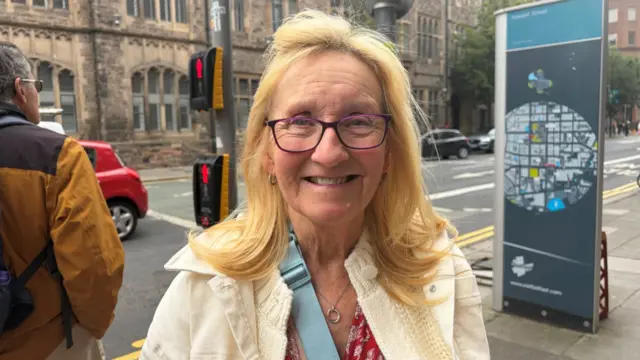 a woman in a cream jacket smiling at the camera