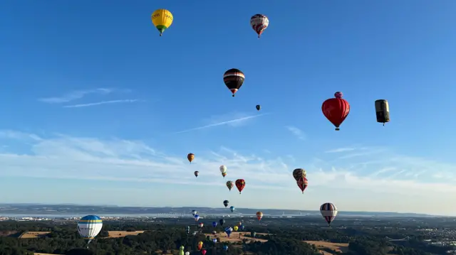 Lots of multi-coloured and multi-shaped balloons in the sky above Ashton Court.