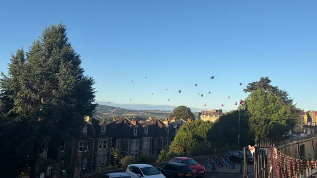 Dozens of balloons rise into the sky above the terraced houses of Clifton.