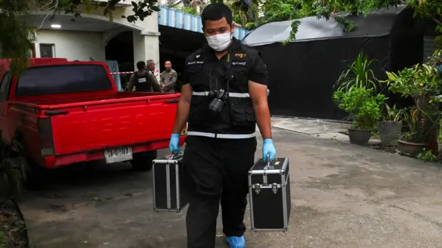 A man carries two boxes as he exits the property