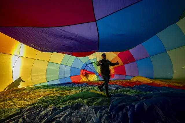 A man stands inside a multi-coloured balloon.