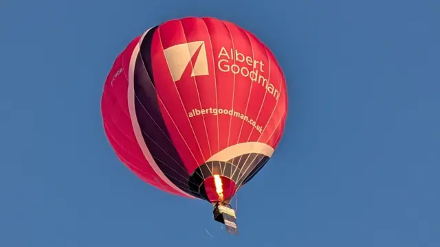 A red balloon against a light blue sky.