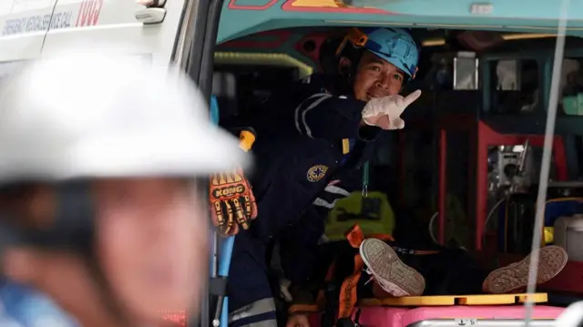 A paramedic gestures from inside an ambulance