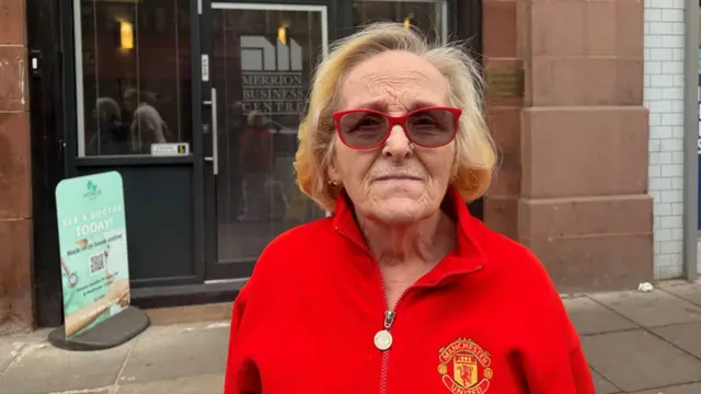a woman in a Manchester United top, looking at the camera