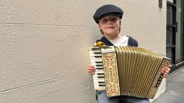 A young boy plays the accordion in a Belfast street