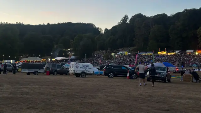 Teams of balloonists line their vehicles and baskets up in the main arena at the Bristol Balloon Fiesta at dusk
