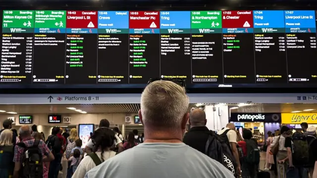 Passengers look towards the departure boards as trains are cancelled and delayed from leaving Euston after a major disruption to rail service in the midlands and north-west England on 6 August 2026