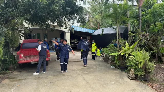 Officials in blue uniforms stand on the driveway of the residence