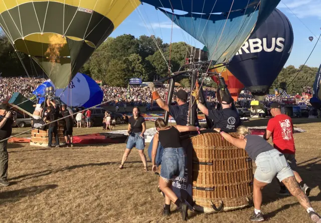 People push hard on a hot air balloon basket as it is inflated ready to take off from the Bristol Balloon Fiesta