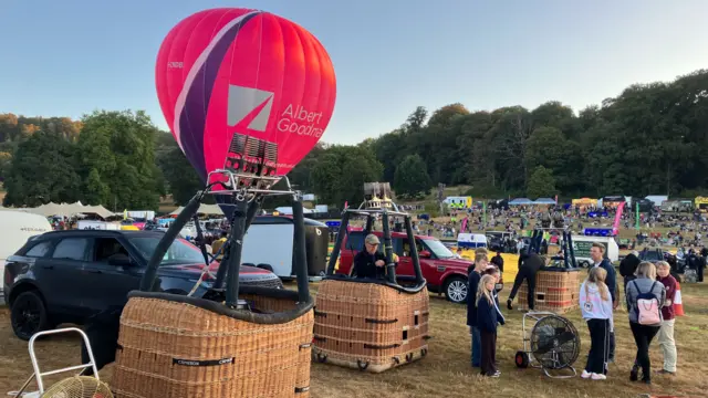 Crowds can be seen as the baskets and balloons prepare to inflate.