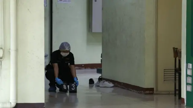 A person with a hair net and mask set up numbered cards on the ground