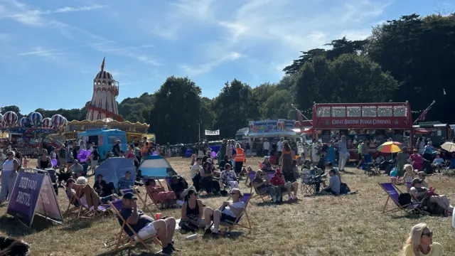 Crows at Ashton Court with people sitting in deck chairs in front on a bus and helter skelter
