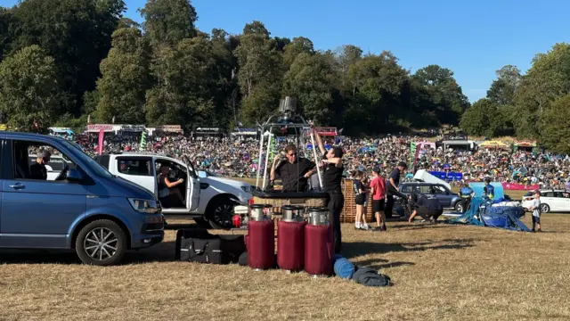 Cars and balloon baskets as people prepare for the mass ascent, with the crowds in the background