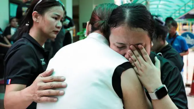 A teacher reacts while embracing a person at Debsirin Nonthaburi School