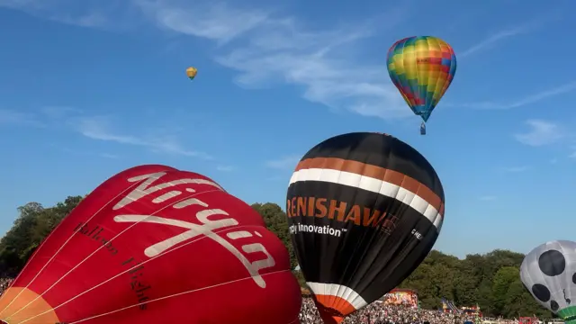 Two balloons are in the air while two others are being prepared on the ground.