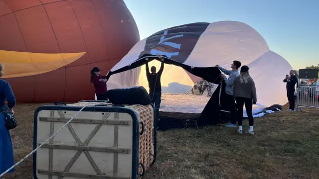 A team of people inflate a black and white balloon.