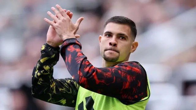 Bruno Guimaraes of Newcastle United applauds the fans as he warms up on the sideline