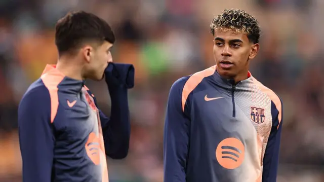 Lamine Yamal of FC Barcelona interacts with teammate Pedri whilst warming up