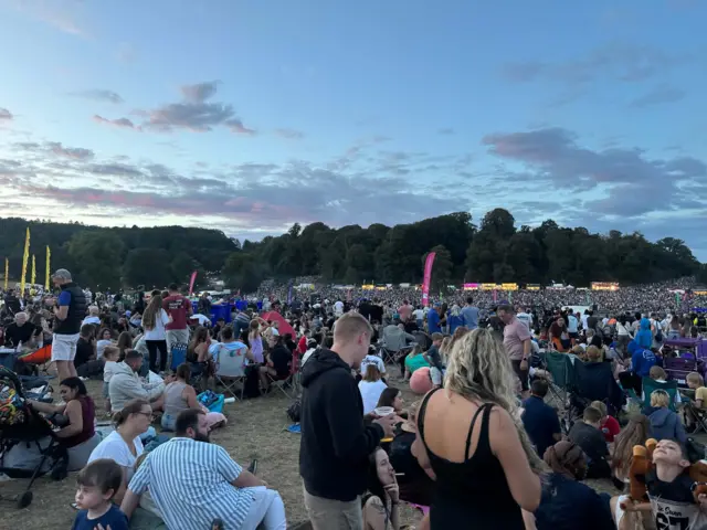 A large crowd of people sat in a field