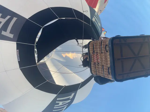 A balloonist using the burner, seen from below as they take off.