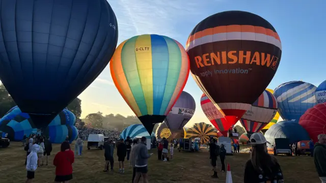 A mass of multi-coloured balloons inflated in a busy arena.