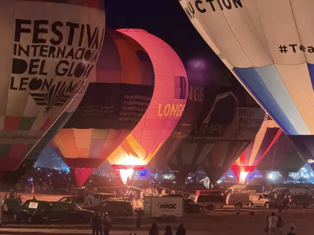 Hot air balloons are illuminated by their burners at night